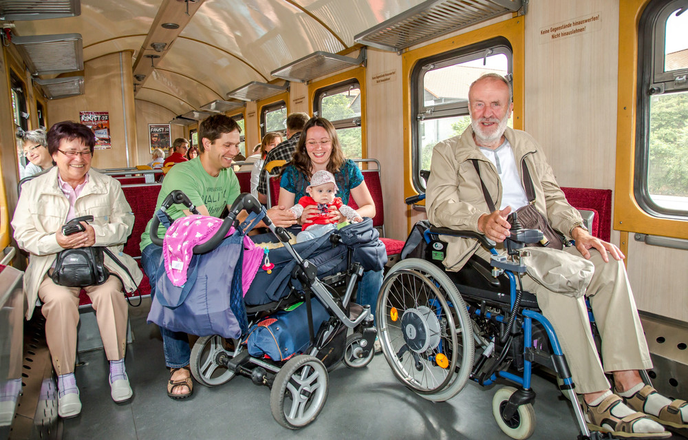 Personen mit Kinderwagen und Rollstuhl im Zug